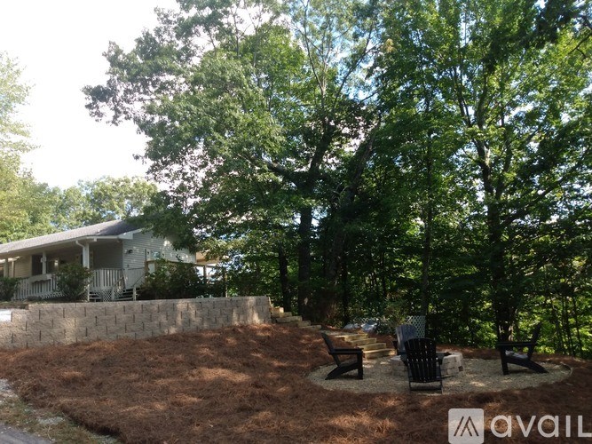 A backyard with a house, trees, and a stone wall.