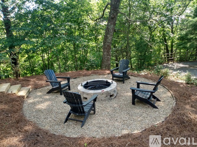 A fire pit surrounded by chairs in a wooded area.
