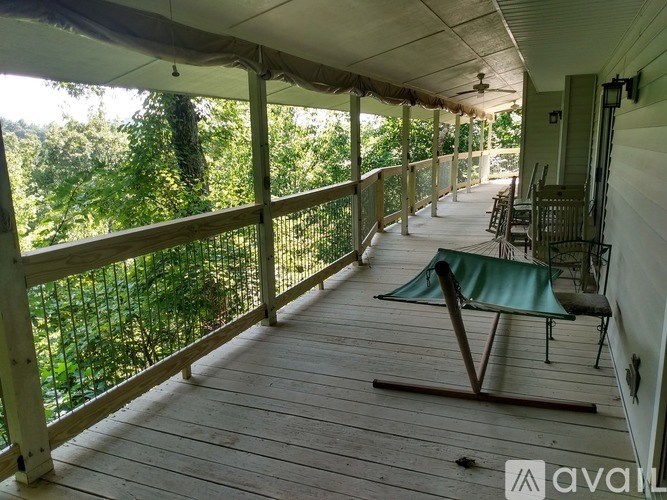 A wooden deck with a table and chairs overlooking a lush green forest.