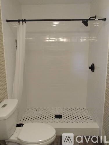 A white toilet with a white shower curtain and a black and white floor.