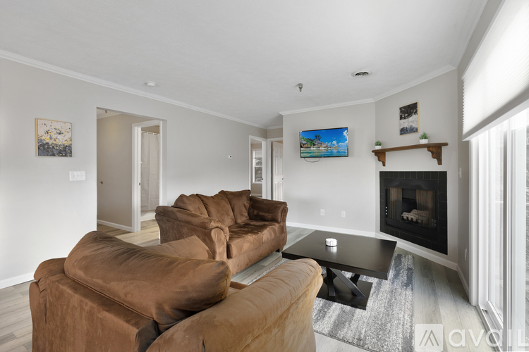 A living room with a brown couch and a fireplace.