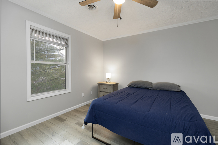 A bedroom with a bed, nightstand, and window.