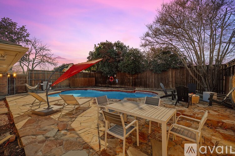 A backyard with a pool and patio furniture.