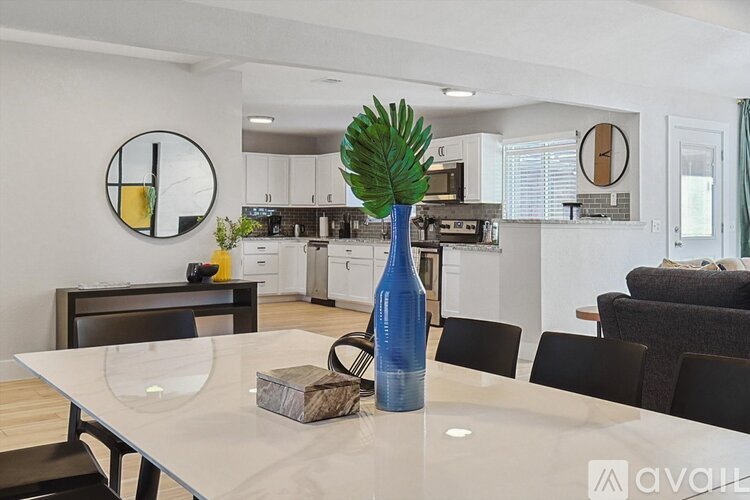 A modern kitchen with a dining table set with a blue vase and a plant.