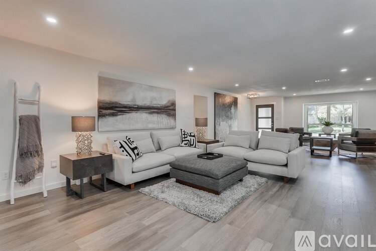 A modern living room with a large painting on the wall and a variety of seating options.