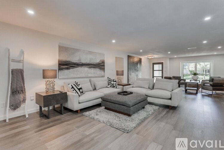 A modern living room with a large painting on the wall and a variety of seating options.