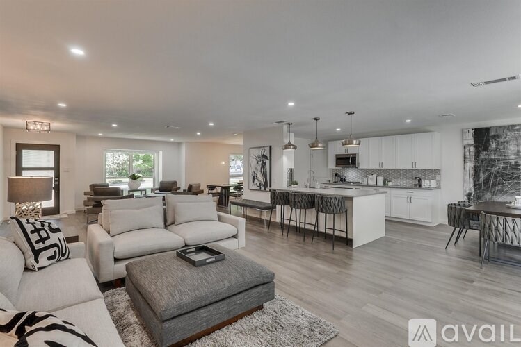 A modern living room with a grey ottoman and a grey and white striped rug.