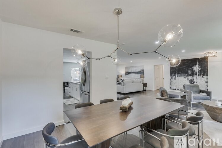 A modern dining room with a wooden table and grey chairs.