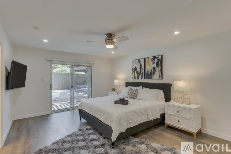 A bedroom with a large bed, a flat screen TV, and a ceiling fan.