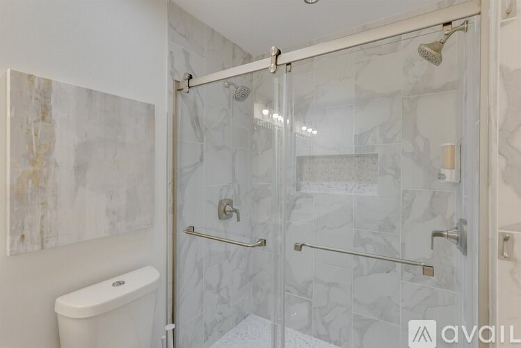 A bathroom with a glass shower door and a white toilet.