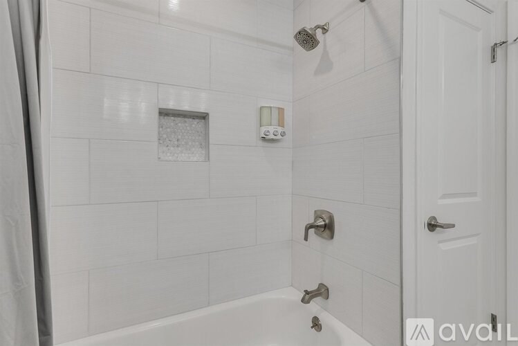 A white bathroom with a tub, shower, and a white door.