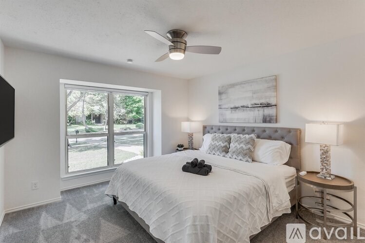 A bedroom with a large bed, a ceiling fan, and a window with a view of the outside.