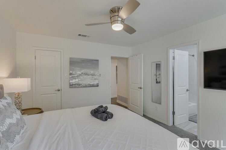 A bedroom with a bed, a ceiling fan, and a painting on the wall.