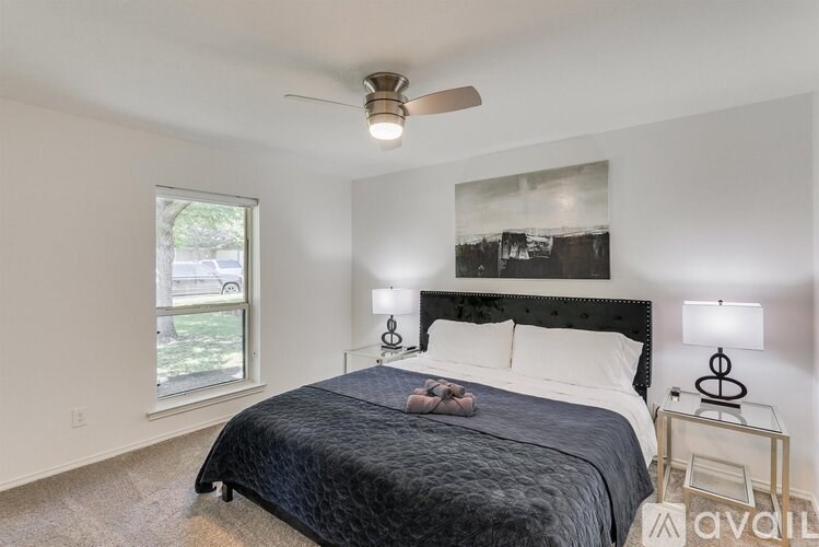 A bedroom with a bed, nightstand, and window.
