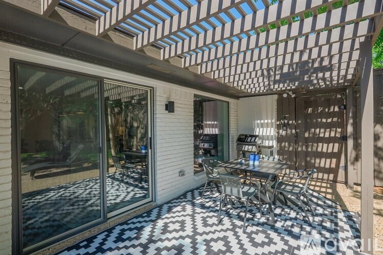 A patio with a table and chairs under a pergola.