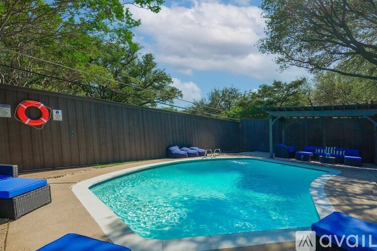 A pool with a blue tiled edge and a red life preserver on the fence.