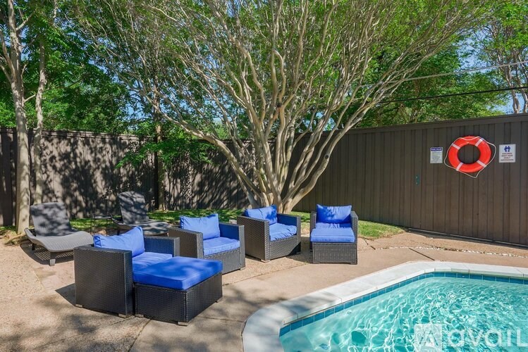 A pool area with a blue cushioned chair and a red life preserver on the wall.