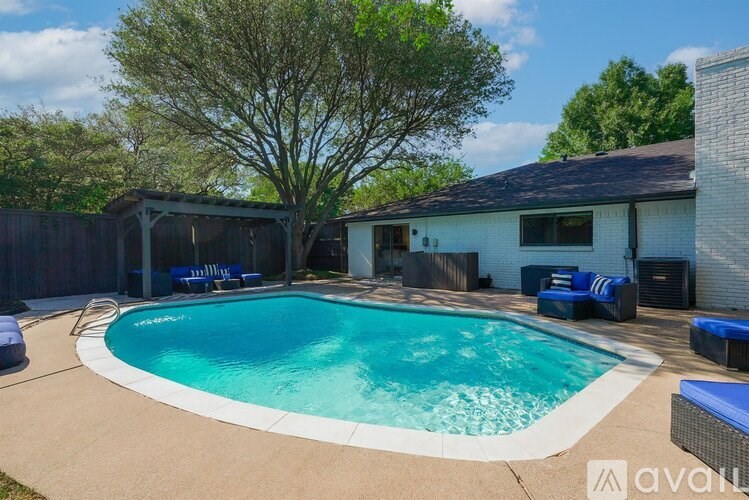A swimming pool in a backyard with a tree and a house in the background.