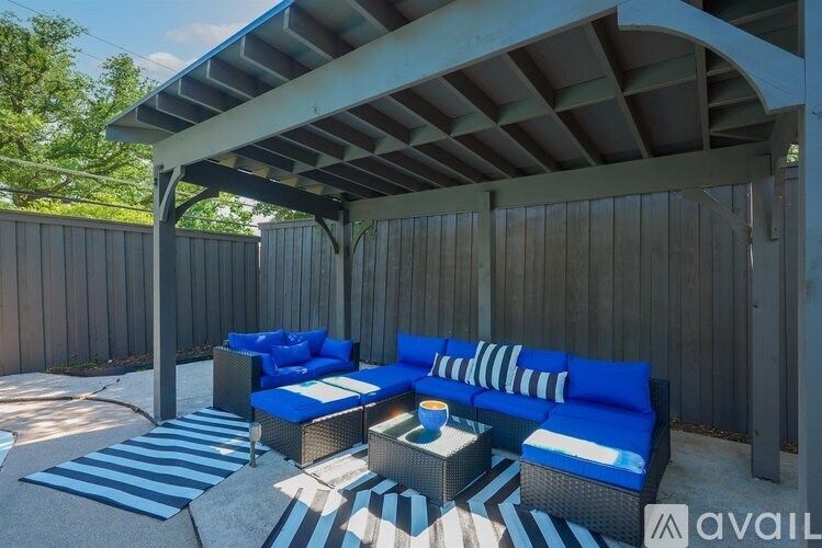 A patio with a blue and white striped rug and furniture.