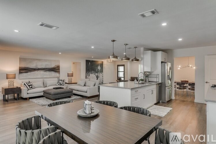 A modern living room with a dining area and kitchen in the background.