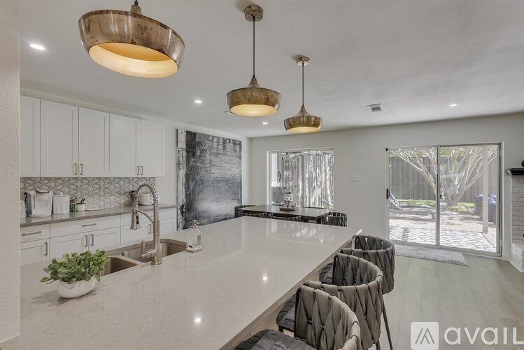 A modern kitchen with a large island and pendant lights.