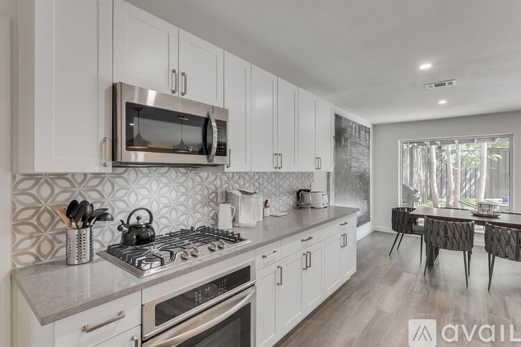 A modern kitchen with a stove, microwave, and a dining table.