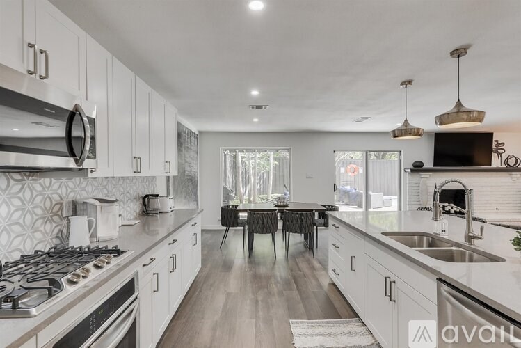A kitchen with a dining table and chairs in the middle.