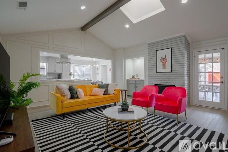 A living room with a yellow sofa, red chairs, and a black and white striped rug.