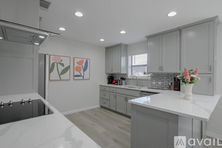 A modern kitchen with a marble countertop and grey cabinets.
