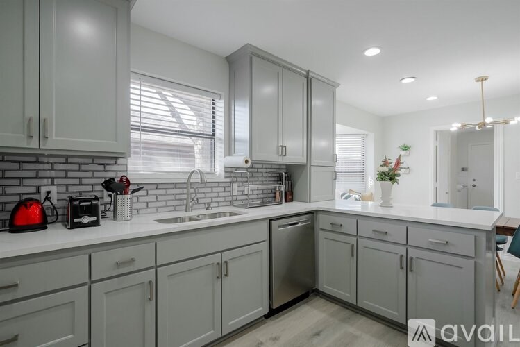 A kitchen with grey cabinets and a white countertop.
