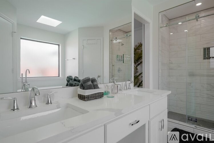 A white bathroom with a double sink and a mirror.