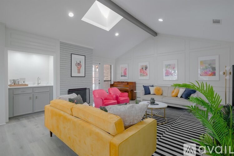 A living room with a yellow sofa and a striped rug.