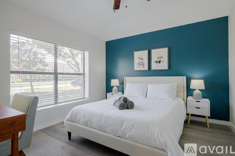 A bedroom with a white bed and a wooden table.