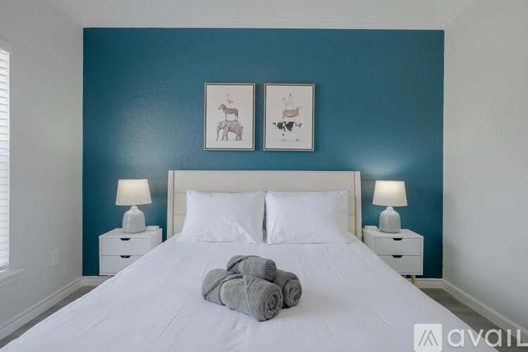 A bedroom with a white bed and two lamps on either side.