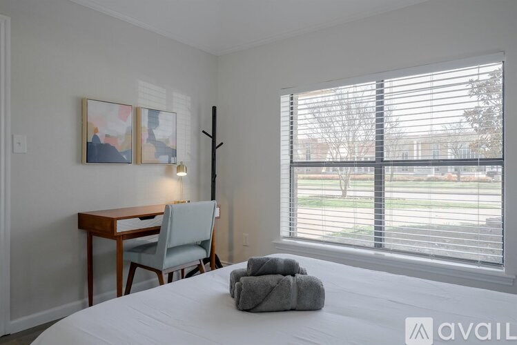A bedroom with a bed, desk, chair, and window with blinds.