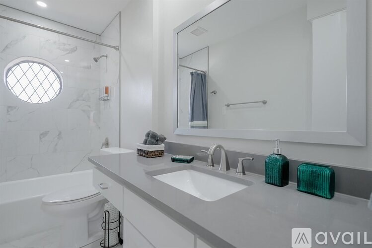 A bathroom with a white tub, sink, and a round window.