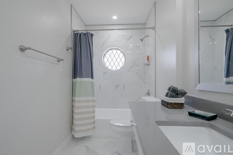 A bathroom with a white tub and a round window.