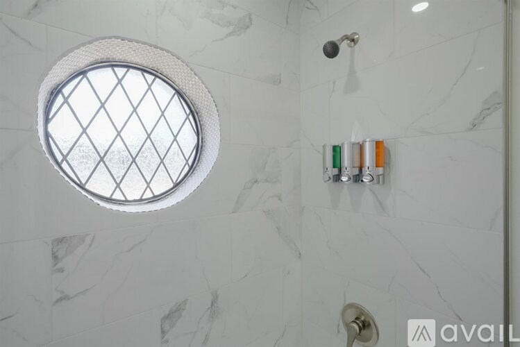 A bathroom with a marble wall and a round window.