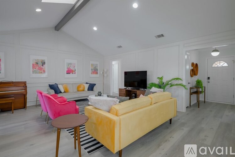 A living room with a yellow sofa and a pink chair.