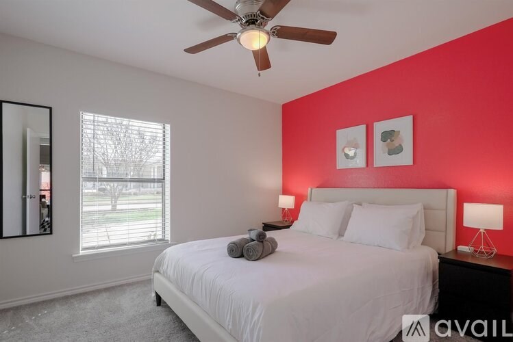 A bedroom with a white bed and a ceiling fan.