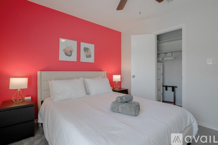 A bedroom with a white bed and two framed pictures on the wall.