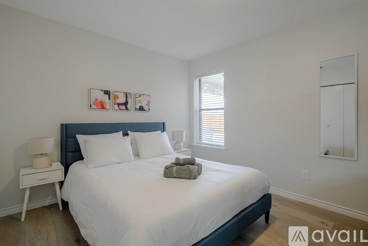 A bedroom with a large bed and a nightstand with a lamp.