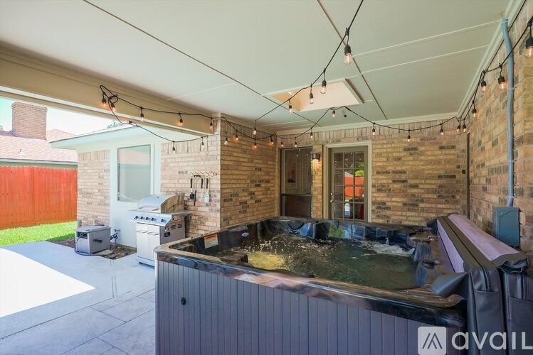 A hot tub is in the middle of a covered outdoor area.