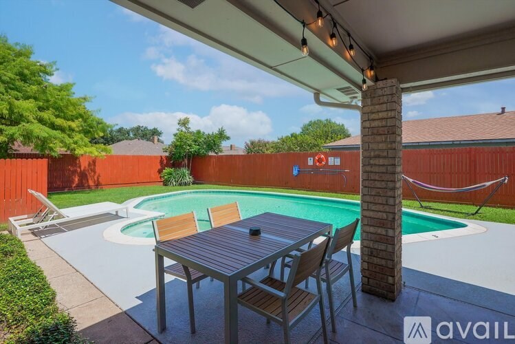 A patio with a table and chairs overlooking a pool.