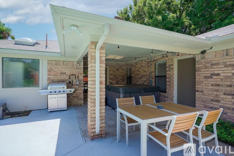 A patio with a table and chairs is covered by a white roof.
