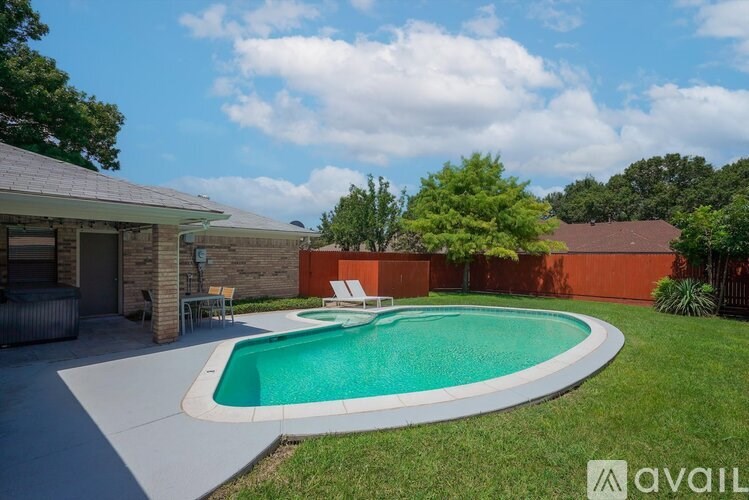 A swimming pool in a backyard with a patio and a house in the background.