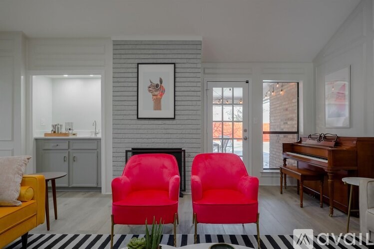 Two red chairs are in the middle of a room with a fireplace and a painting on the wall.