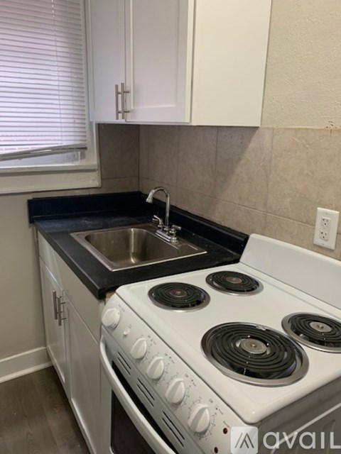 A white stove top oven with a black stovetop sits in a kitchen.