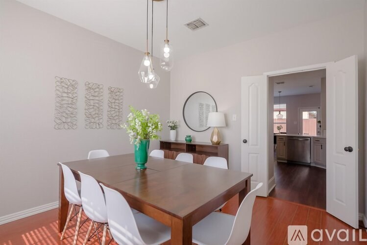 A dining room with a wooden table and white chairs.