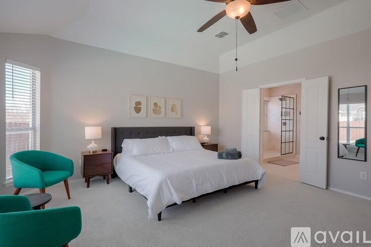 A bedroom with a large bed, a ceiling fan, and a green chair.